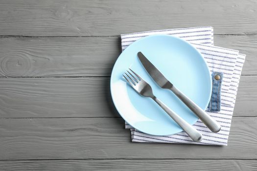 Kitchen towel with cutlery on wooden background, top view