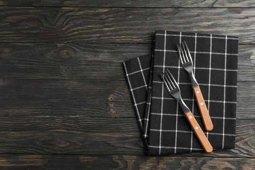 Kitchen towel with cutlery on wooden background, top view