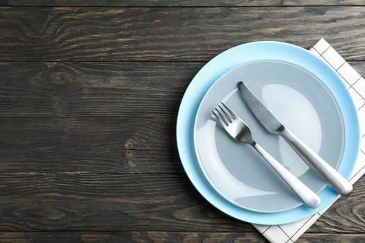 Kitchen towel with cutlery on wooden background, top view