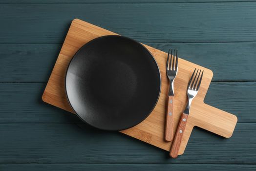 Cutting board and cutlery on wooden background, space for text