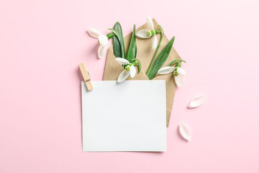 Envelope with snowdrop flowers and paper on color background