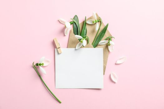 Envelope with snowdrop flowers and paper on color background