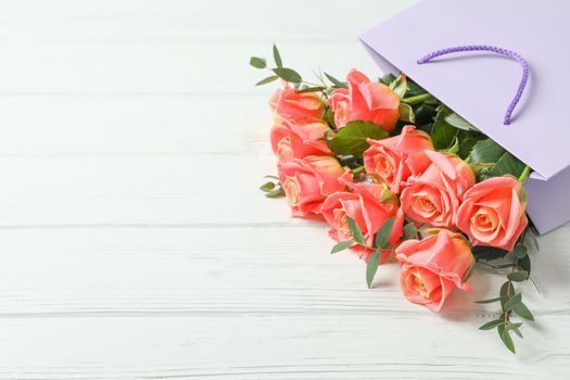 Gift bag with bouquet of pink roses on white background, space for text