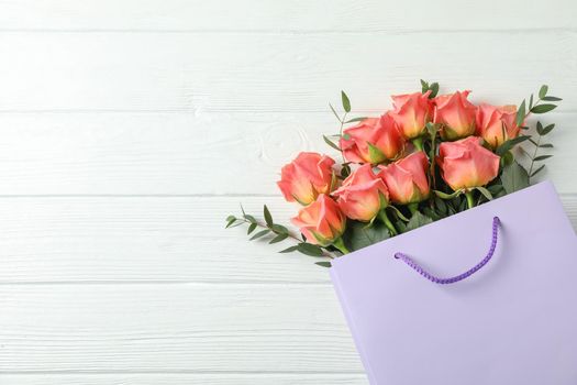 Gift bag with bouquet of pink roses on white background, space for text