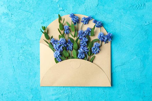 Letter with fresh hyacinths on blue background, top view