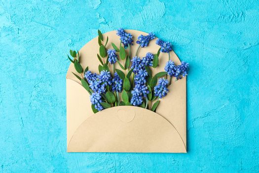 Letter with fresh hyacinths on blue background, top view