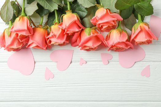 Beautiful orange roses with pink hearts on white background, space for text