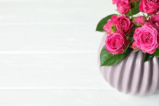 Vase with pink roses and space for text on white background, closeup