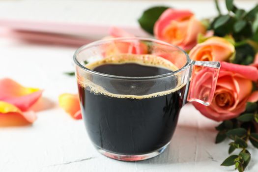 Cup of coffee and pink roses on white background, closeup