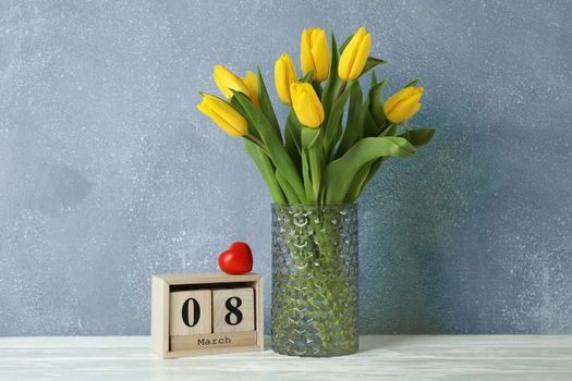 Beautiful yellow tulips in a glass vase on white background for Mother's Day