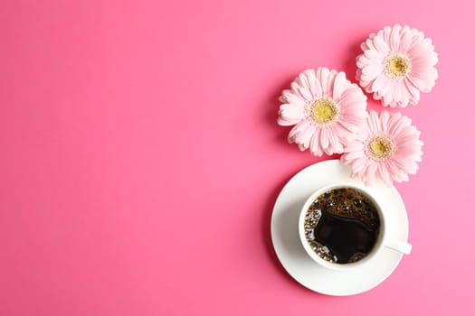 Beautiful pink gerbera flowers and cup of coffee on color background, top view. Space for text