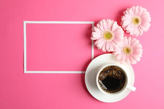 Beautiful pink gerbera flowers, cup of coffee and frame on color background, top view. Space for text