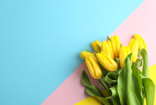 Beautiful bouquet of yellow tulips on color background, top view. Space for text