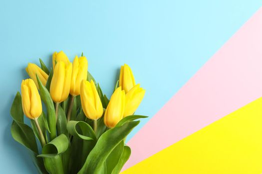 Beautiful bouquet of yellow tulips on color background, top view. Space for text