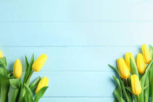 Beautiful fresh yellow tulips on wooden background, top view