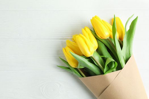 Beautiful bouquet of yellow tulips on wooden background, top view