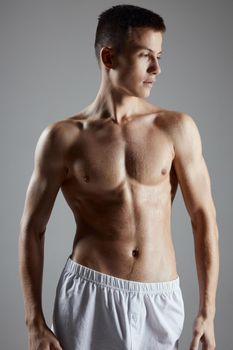portrait of a young athlete with a pumped-up torso on a gray background. High quality photo