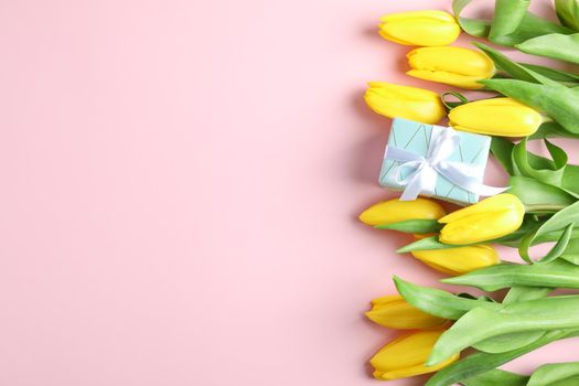 Beautiful fresh yellow tulips with gift on color background