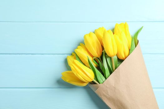 Beautiful bouquet of yellow tulips on wooden background, space for text