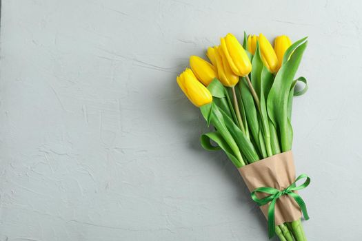 Beautiful bouquet of yellow tulips on grey background, top view. Space for text