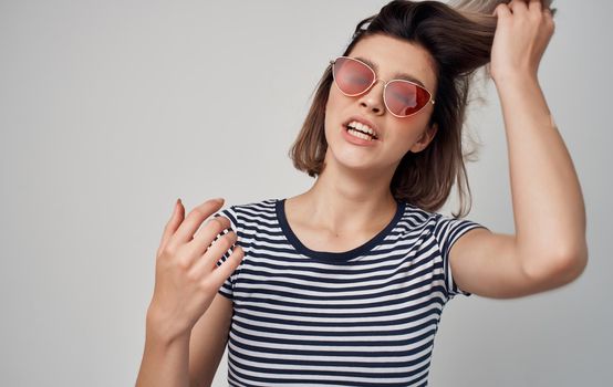 beautiful woman with glasses and striped t-shirt red skirt gray background. High quality photo