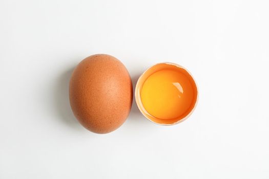 Whole egg and half egg with yolk on white background, space for text and top view