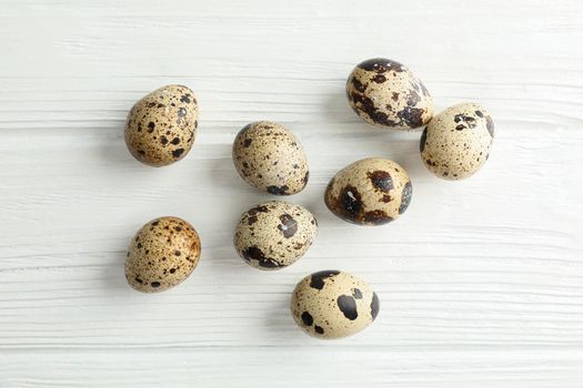 Flat lay composition with quail eggs on white wooden background, space for text