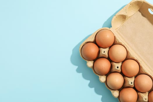 Brown eggs in carton box on color background, space for text and top view