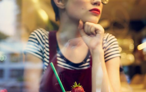 fashionable woman in red sundress sits in a cafe and mirror glass reflection of cars on the street. High quality photo