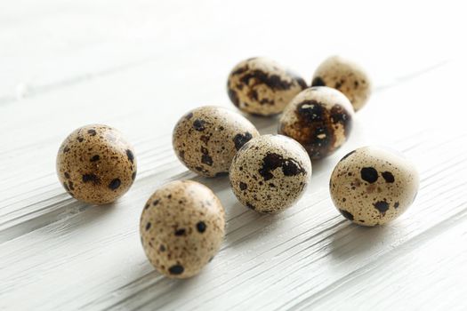 Quail eggs on white wooden background, space for text and closeup