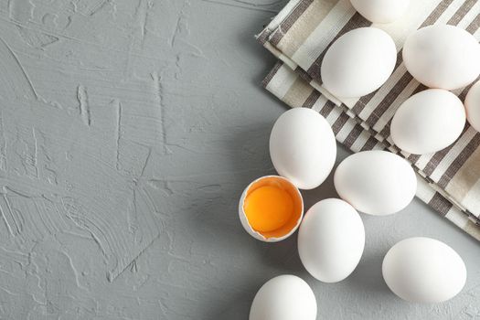 White chicken eggs in kitchen towel on grey background, space for text and top view