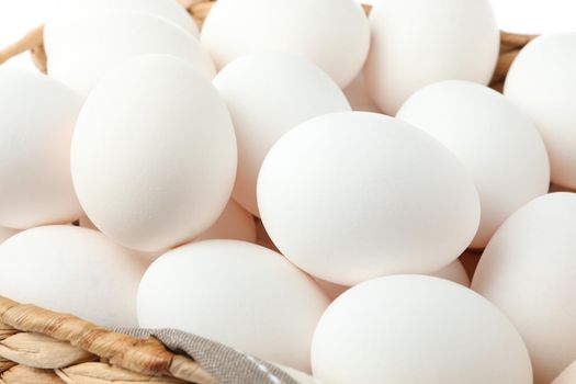 Chicken eggs with kitchen towel in straw basket as background, closeup