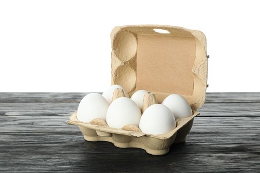 White chicken eggs in carton box on wooden table isolated on white background, space for text