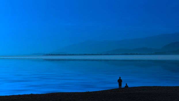 Seascape blue evening and silhouettes of people on the beach.
