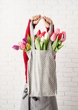 Eco friendly, zero waste concept. Spring shopping. Woman holding gray polka dot fabric bag with colorful tulips