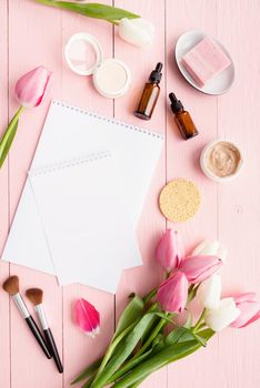 Celebration and holydays concept. Top view of cosmetics and pink and white tulips with greeting card for mock up top view flat lay on pink wooden background