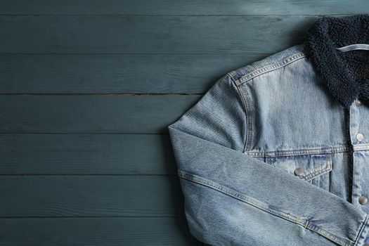 Denim jacket on wooden background, space for text