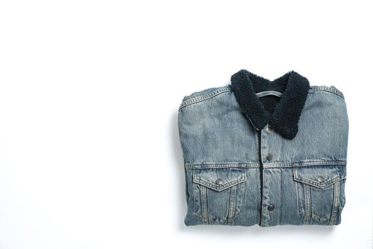 Folded denim jacket on white background, space for text
