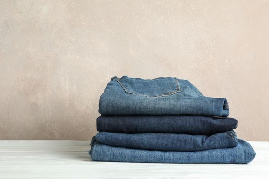 Stack of jeans pants on white background, space for text
