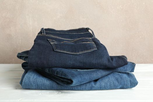 Stack of jeans pants on white background, space for text