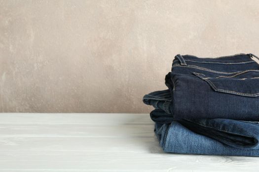 Stack of jeans pants on white background, space for text