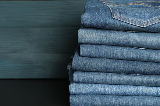 Stack of jeans pants on black table, space for text