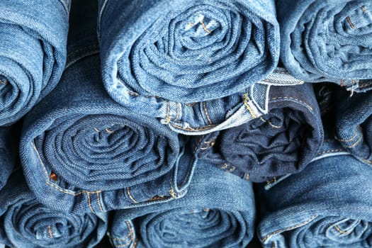 Stack rolled jeans texture on whole background, close up