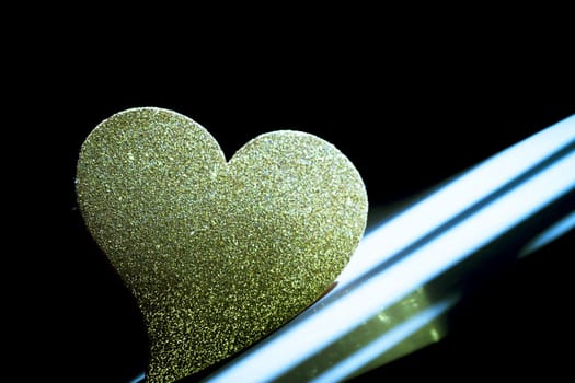 Golden shiny heart on black background