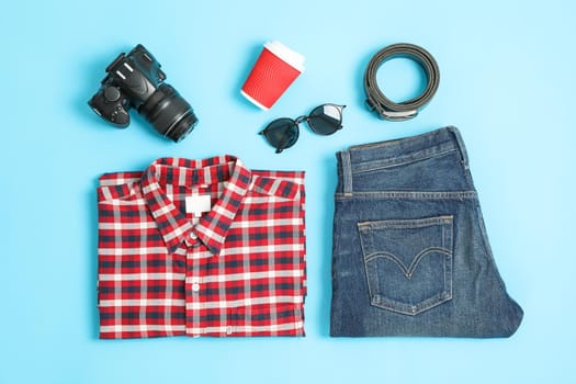 Flat lay composition with shirt, jeans, glasses and camera on color background