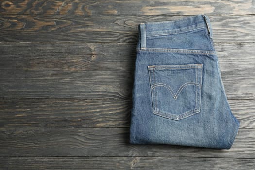 Blue jeans folded on a wooden background, space for text