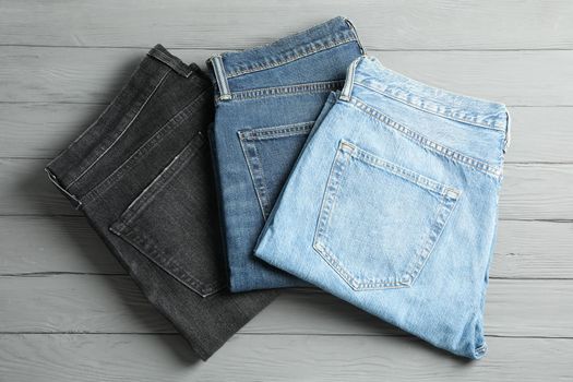 Different jeans on grey wooden background, space for text