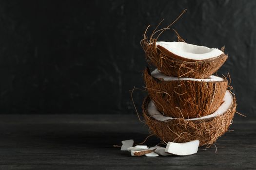 Stack tropical coconut on wooden table against black background, space for text