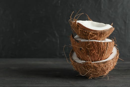 Stack tropical coconut on wooden table against black background, space for text