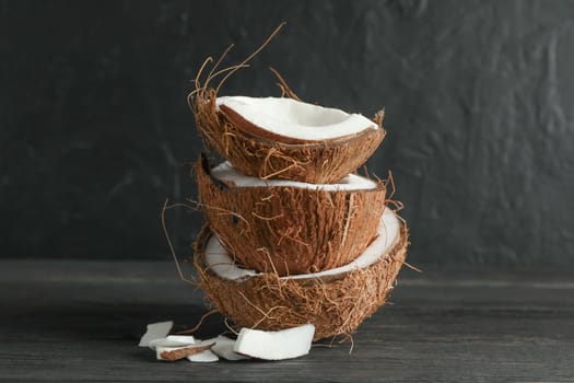 Stack tropical coconut on wooden table against black background, space for text